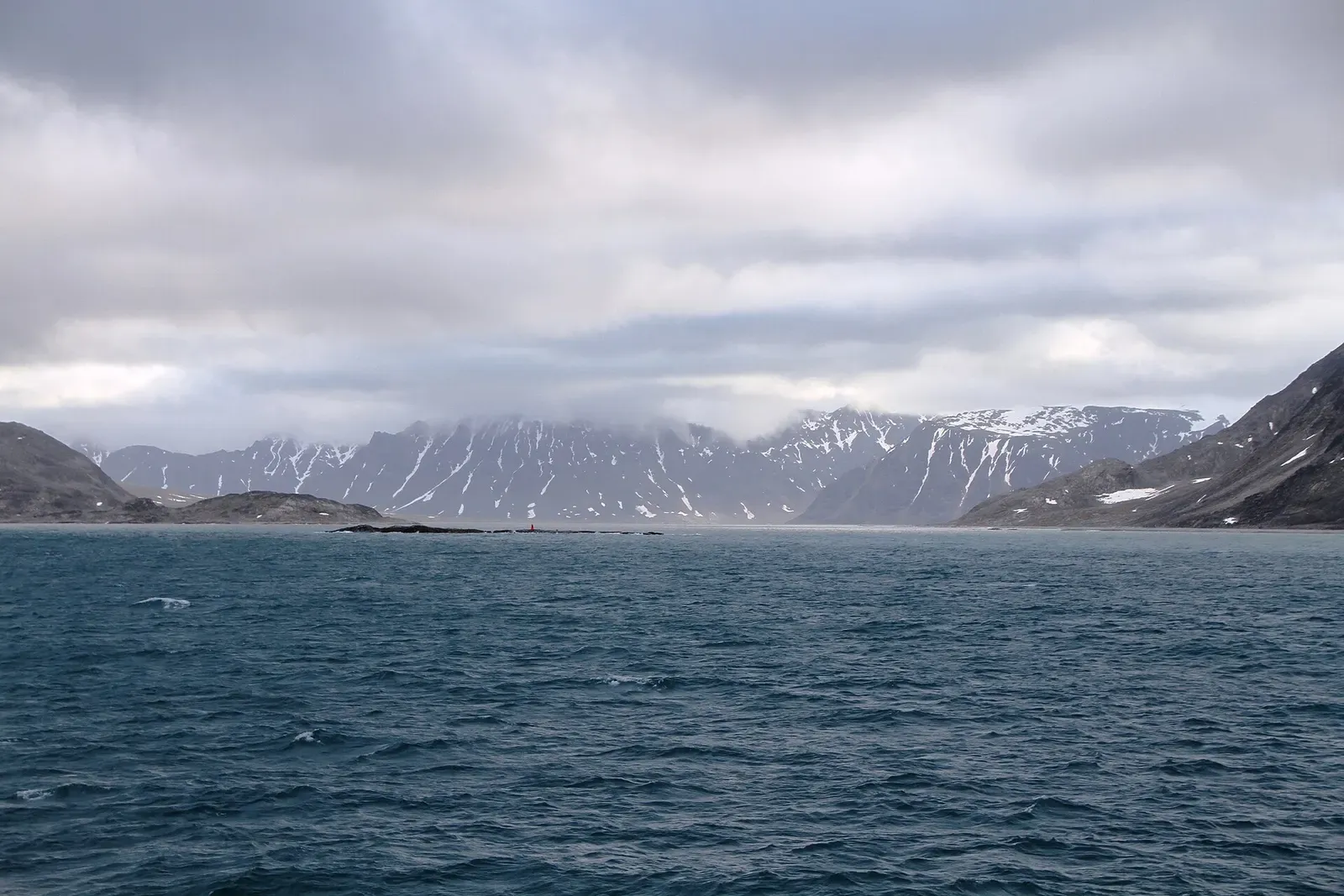 Cloud-wrapped mountains along the shore of Smeerenburgfjorden, viewed from southwest Moseøya — Svalbard.