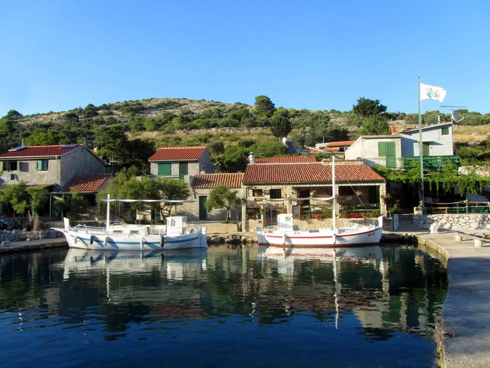 Stone houses and moored fishing boats in Smokvica Vela's sheltered cove — Smokvica Vela Wall, Kornati Islands.