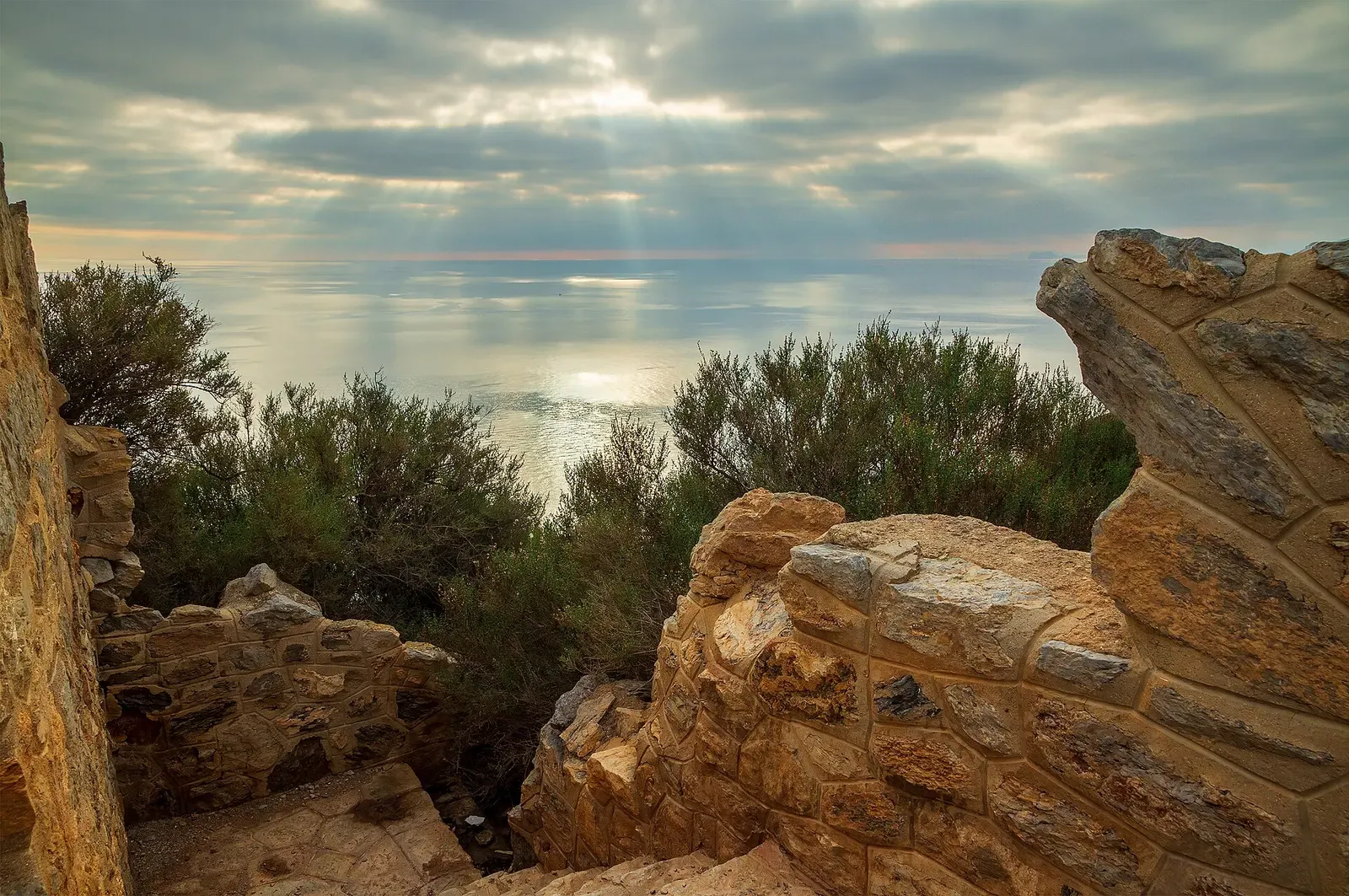 Old stone ramparts frame a view south over the Mediterranean at sunrise near Cabo Tiñoso.