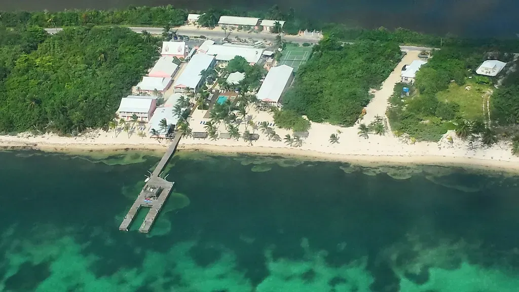 Aerial view of a Little Cayman resort with its dock running out over the shallow turquoise flat