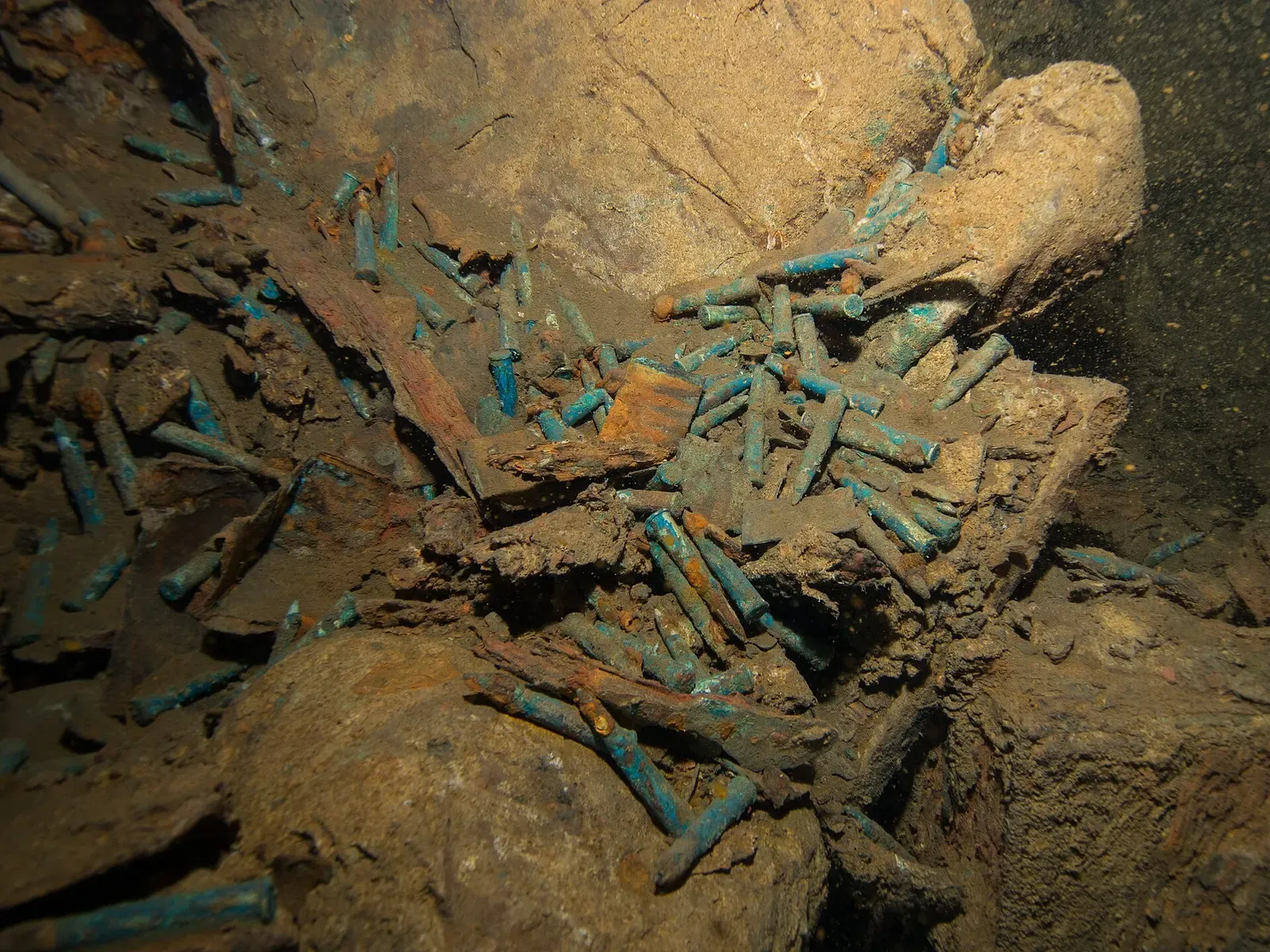 Scattered green-corroded bullet cartridges spilling from a corroded cargo hold — Sudanese Red Sea