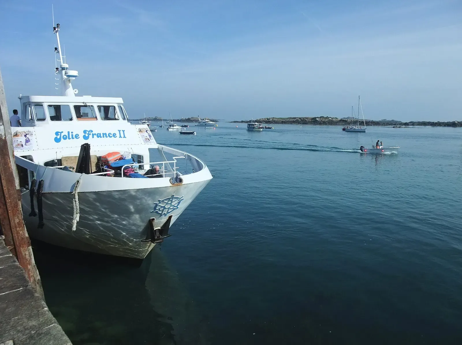 Passenger ferry bow in calm water with boats and low islands beyond — Chausey Islands & Granville