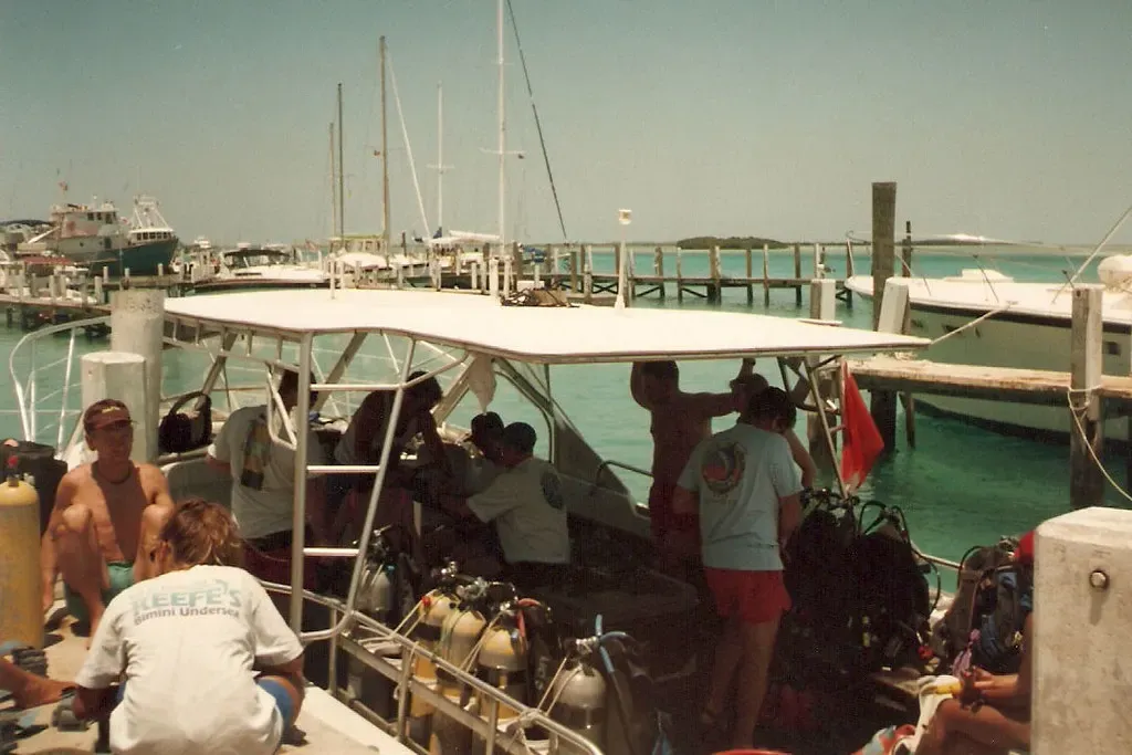 Divers load tanks and gear onto a dive boat tied up at a harbor dock — Bimini.