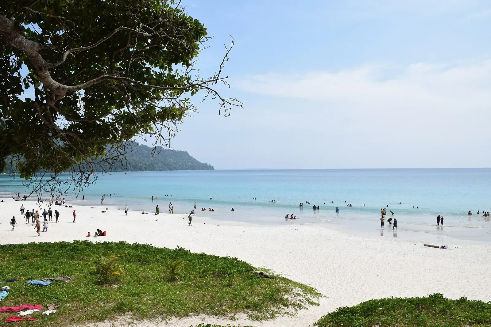 Visitors wading in calm turquoise water off a white sand beach on Havelock Island — Andaman Islands