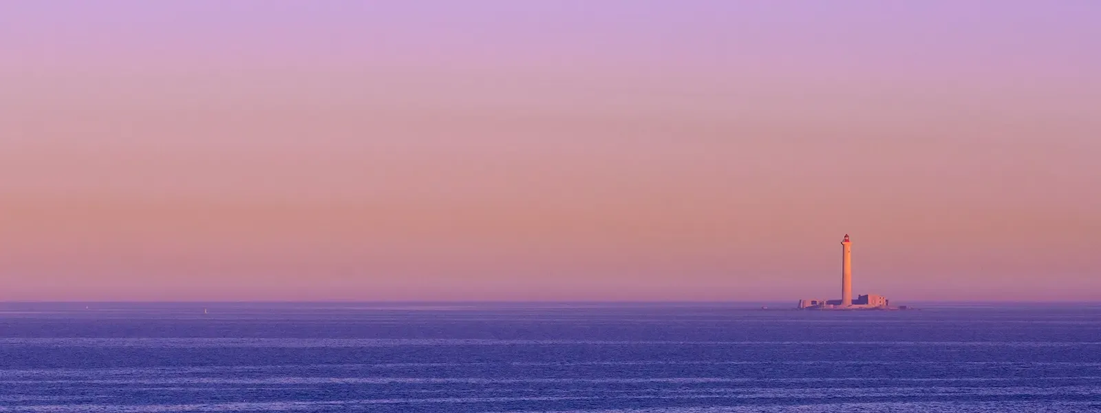 Planier lighthouse silhouetted on the horizon at dusk, seen across open water from Marseille — Le Planier