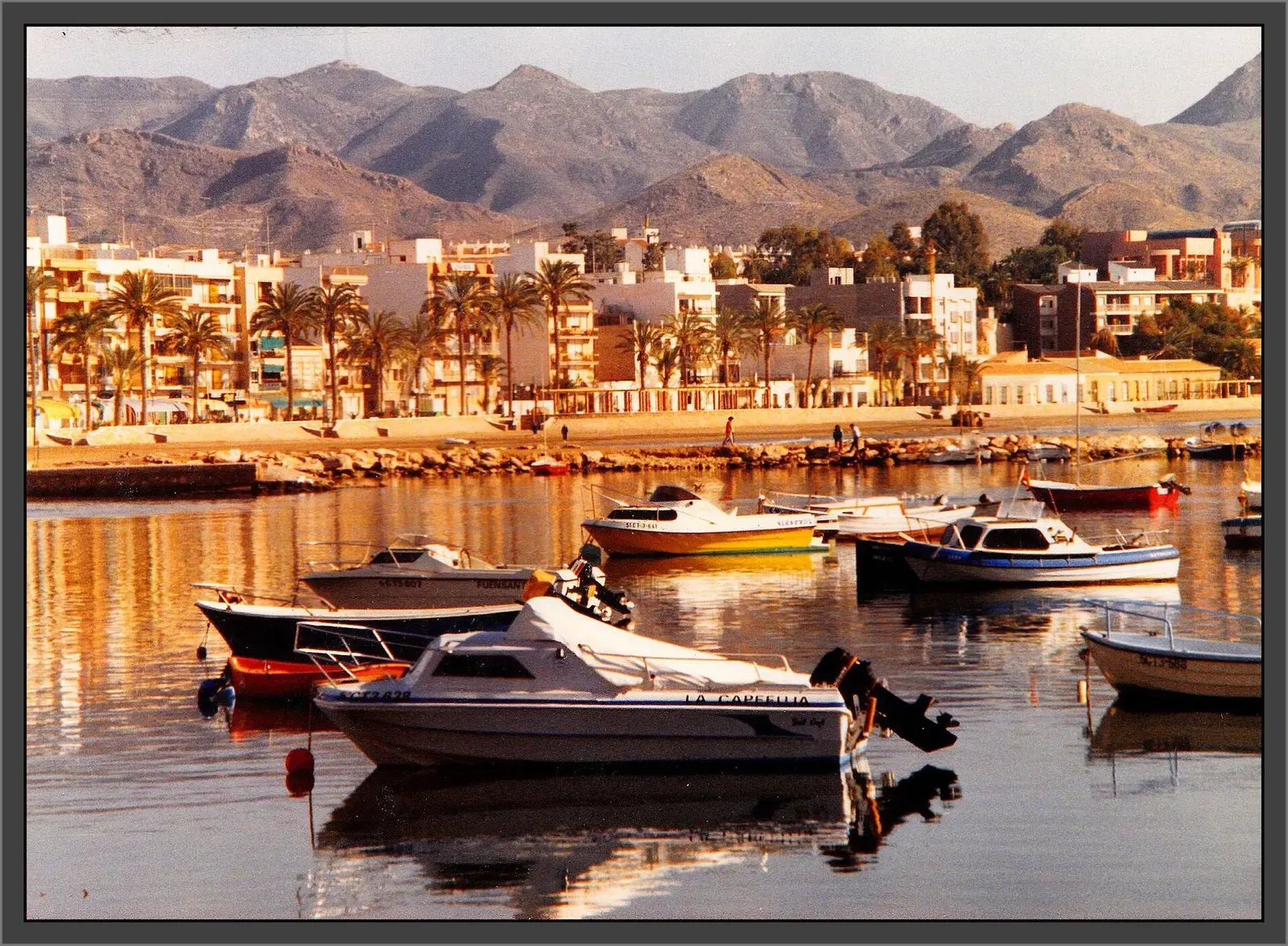 Boats moored in Puerto de Mazarrón harbour with the town and hills behind.
