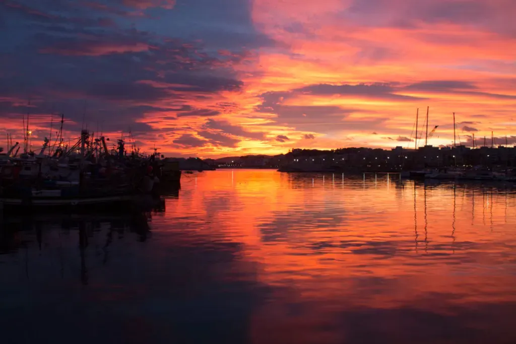 Sunset over the harbour at Blanes, with boats silhouetted on the water.