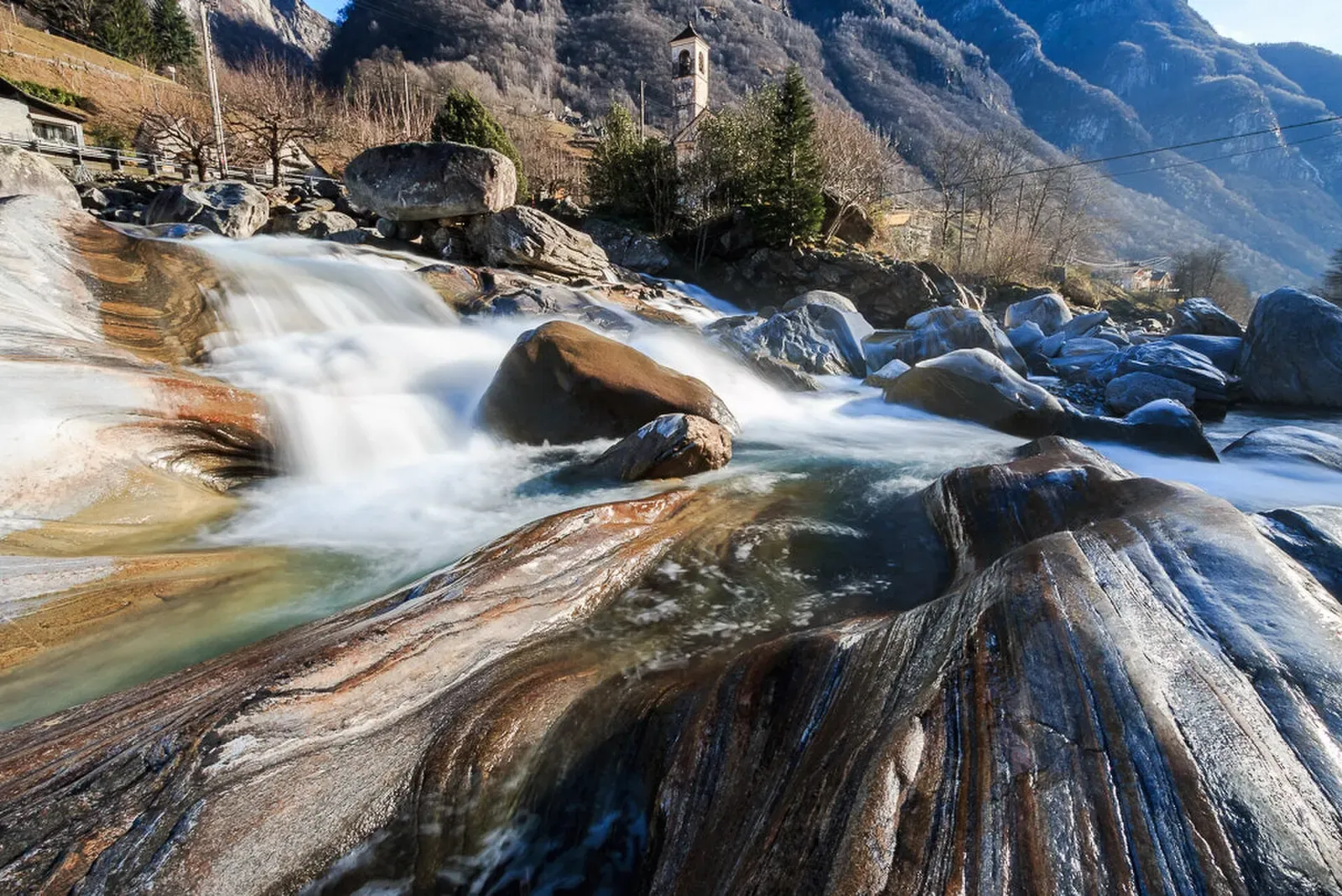 Water cascading over smooth, striated granite slabs worn into curves by glacial meltwater — Verzasca Valley