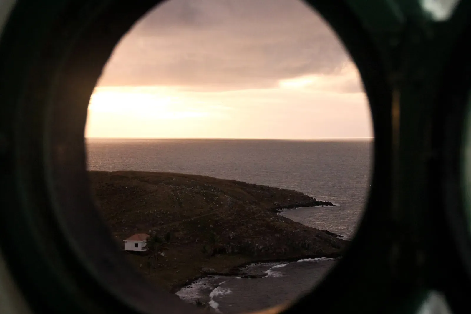An Abrolhos island with a small white house, seen from above through a round window at sunset — Abrolhos Archipelago