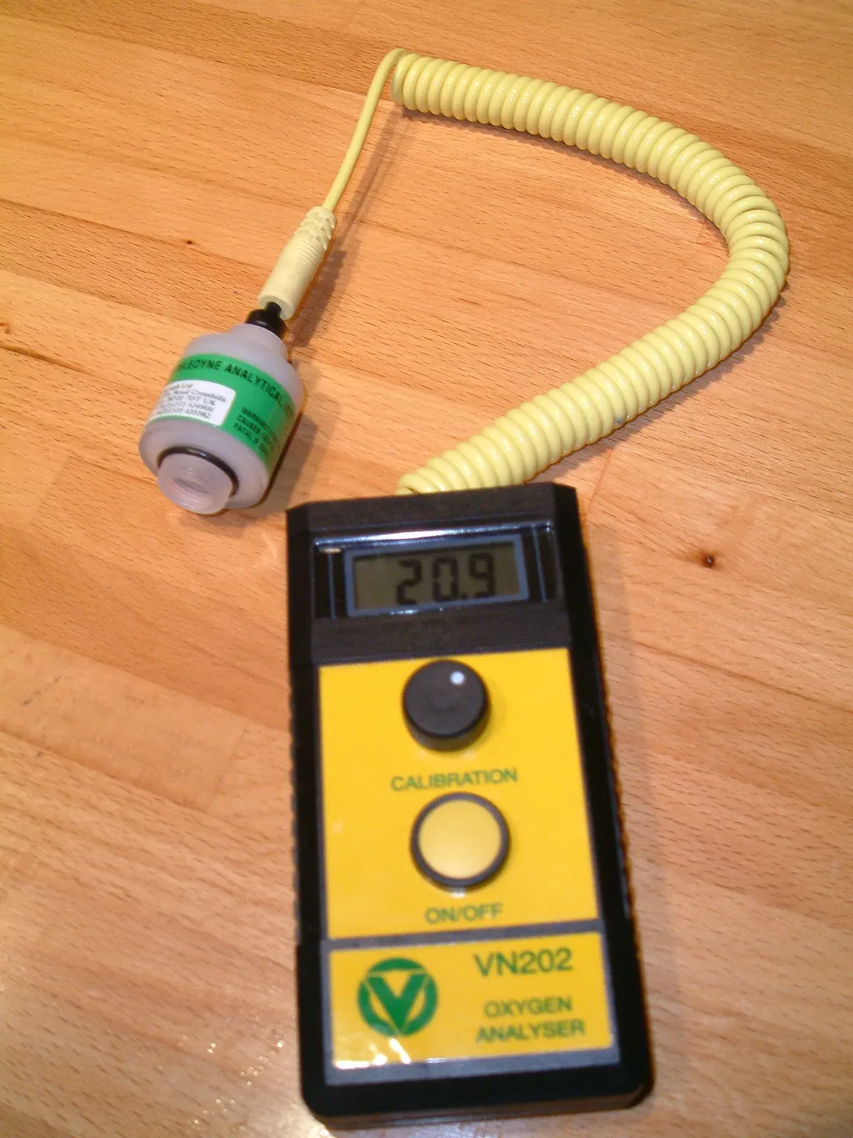 A handheld oxygen analyser reading 20.9 per cent, with its sensor cell on a coiled lead beside it