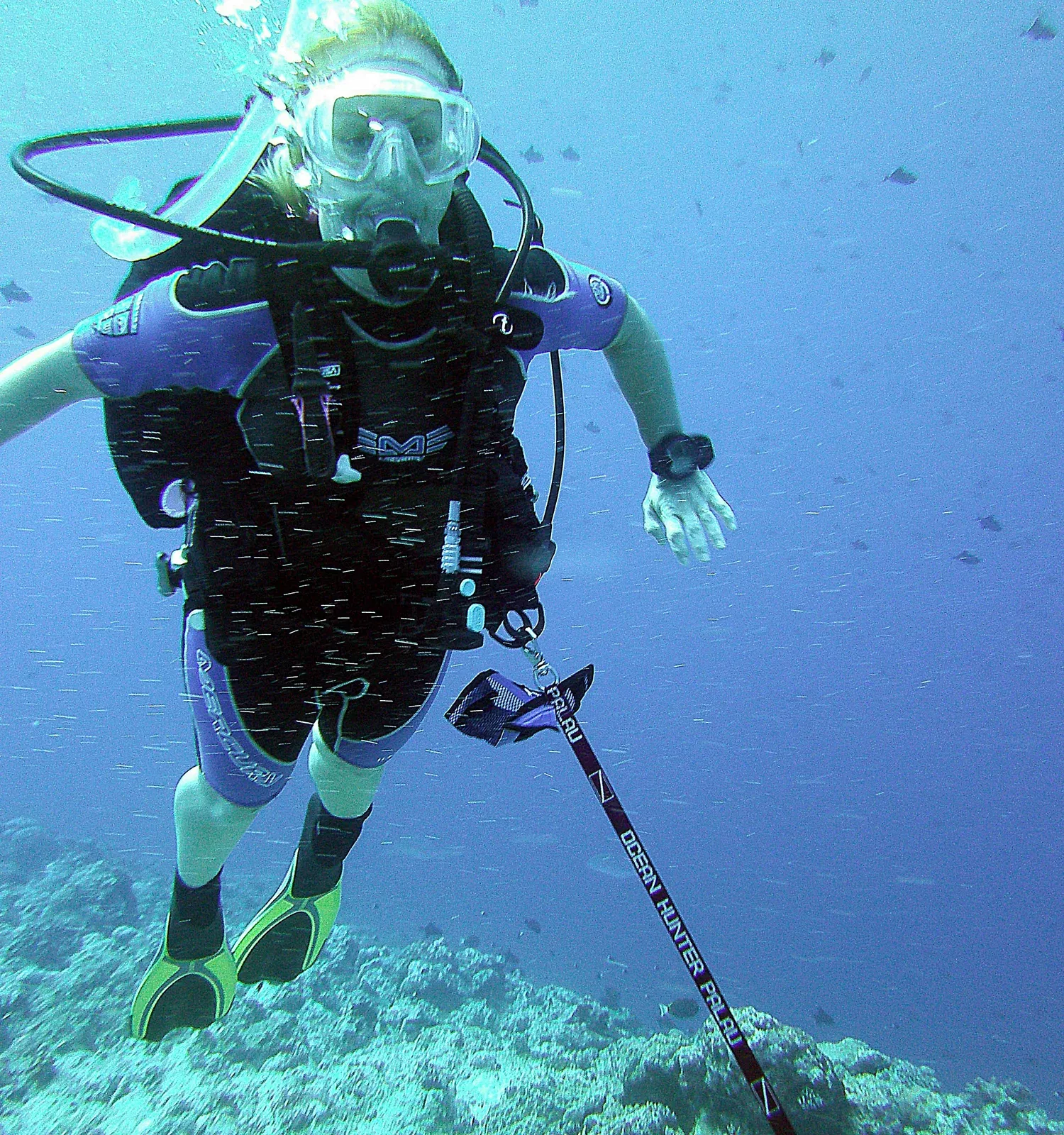 A diver flying horizontally in current at the end of a taut reef hook line clipped to the reef edge