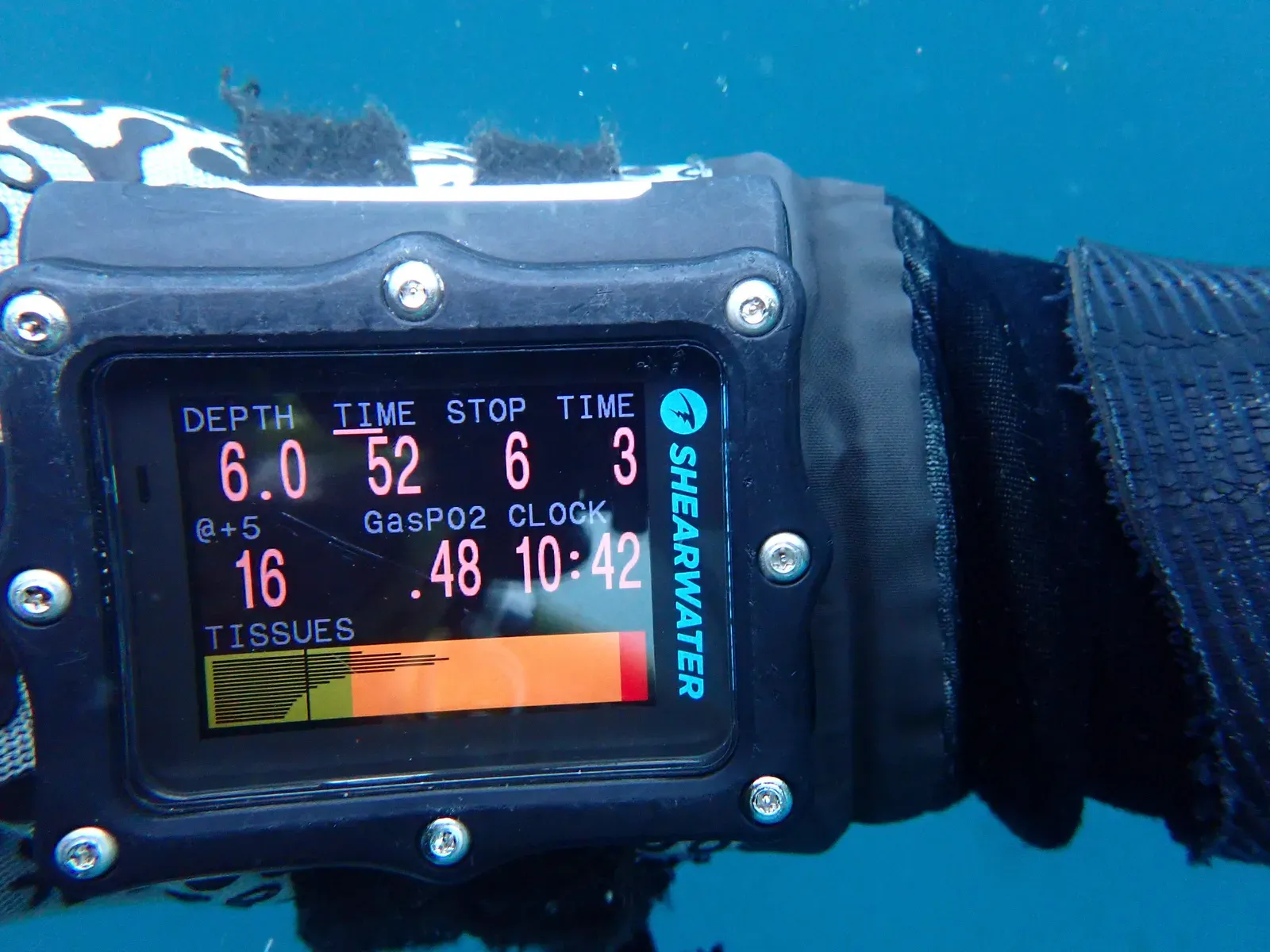 A wrist dive computer at 6 metres showing a three minute stop and a row of coloured tissue loading bars